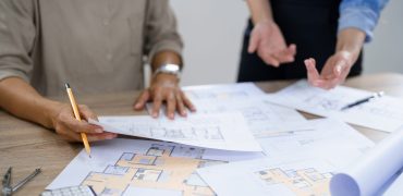 Concept of engineering consulting, Two female engineers discussing about blueprint of condominium.